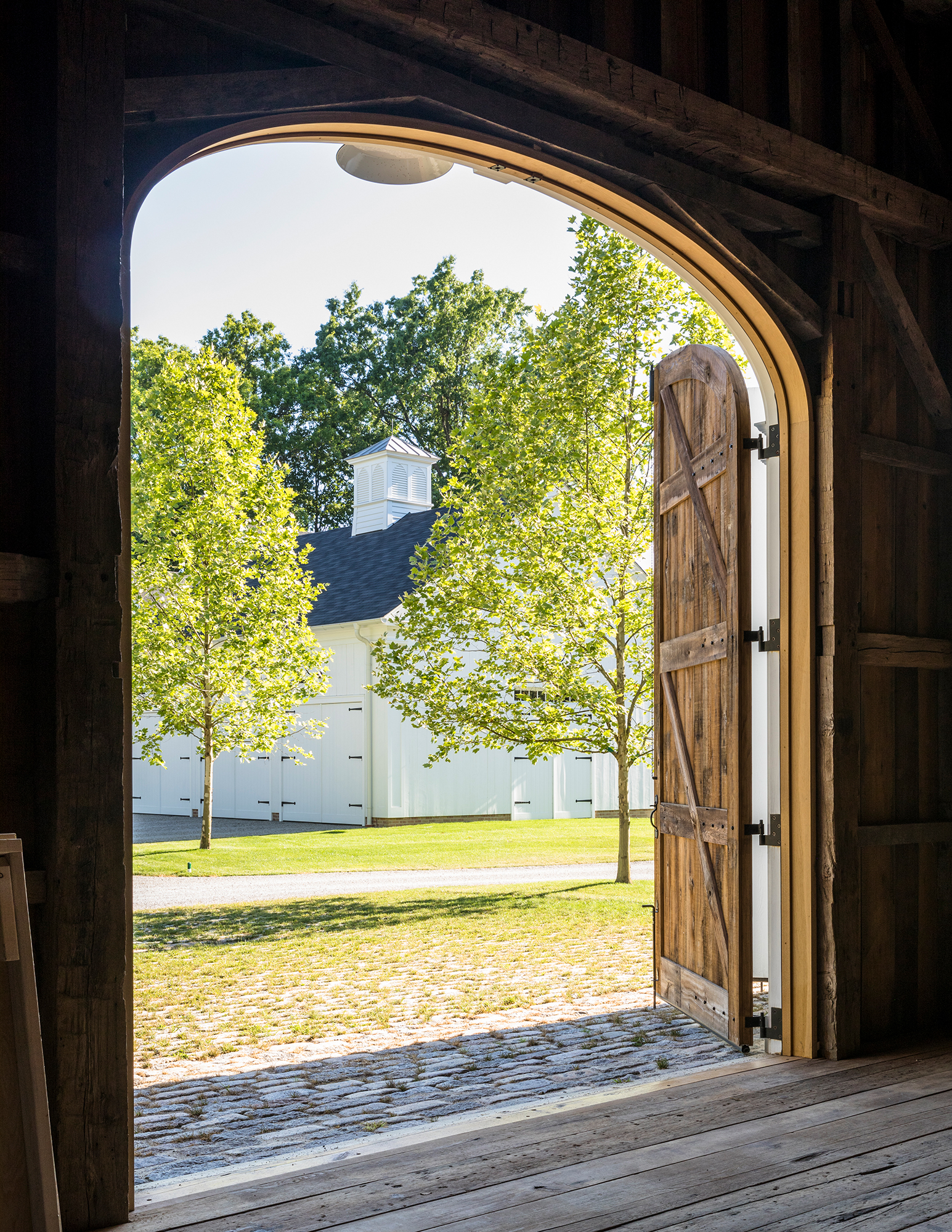 View from within the tractor barn. The paving outside the barn is widely spaced cobblestones planted with grass, providing a durable yet green foreground to the large building.